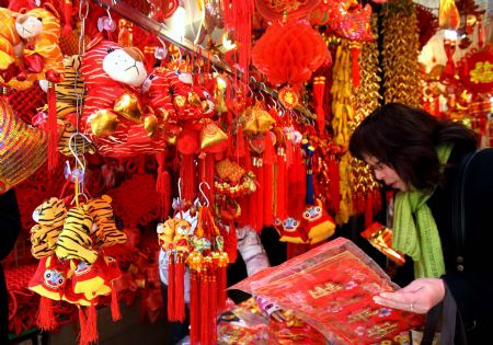 A tourist selects couplets for traditional Chinese Spring Festival outside Yuyuan Garden in Shanghai, east China, Jan. 14, 2010. [Xinhua]