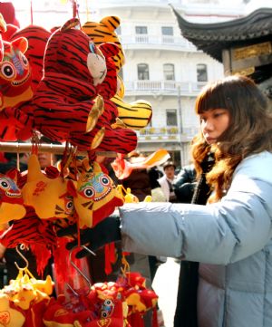 Tourists select tiger dolls for traditional Chinese Spring Festival outside Yuyuan Garden in Shanghai, east China, Jan. 14, 2010. [Xinhua]