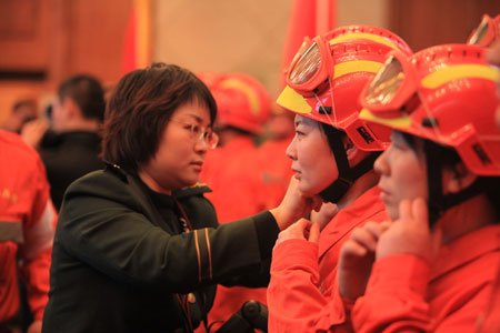 A female armed police official helps fastening helmet of a female member of a Chinese rescue team before the 50-member team&apos;s departure for quake-hit Haiti, at the Capital International Airport in Beijing, capital of China, Jan. 13, 2010. The team consist of search and rescue personnel, who have conducted many rescue tasks of this kind in the past years, and three sniffer dogs.