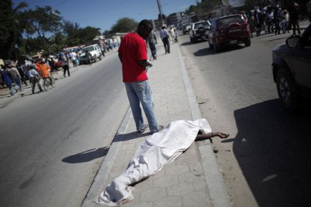 Resident walk next to a dead body after an earthquake in Port-au-Prince January 13, 2010.(Xinhua/Reuters Photo)