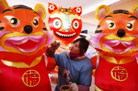 A folk craftswoman decorates a large lantern at a handicraft factory in Rushan, east China's Shandong Province, Jan. 14, 2010.