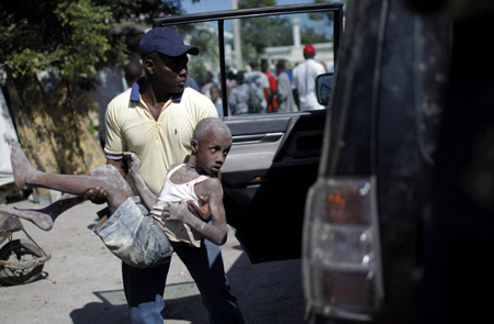 A resident carries Samael Jachond, who was rescued from the remains of his house, four days after a major earthquake hit the capital Port-au-Prince January 15, 2010. [Xinhua]