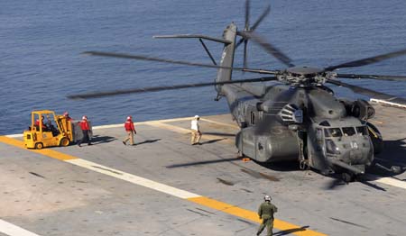 A C-130 transport plane carrying supplies flies past the tower on board the USS Carl Vinson aircraft carrier enroute to Port-au-Prince, Haiti, January 15, 2010. [Xinhua]