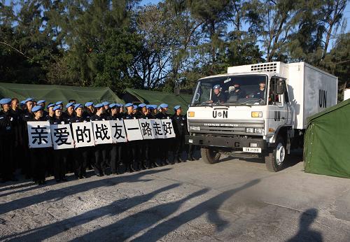 Chinese police officers, holding placards reading &apos;Dear comrades, have a nice trip home&apos; in Chinese, bid farewell to their colleagues who died in the Haiti quake in Port-au-Prince, capital of Haiti, January 17, 2010. The bodies of the eight Chinese police officers are expected to be brought home on Tuesday morning by a chartered plane. [Xinhua]