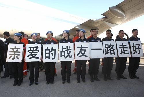 Chinese police officers, holding placards reading &apos;Dear comrades, we are taking you home&apos; in Chinese, bid farewell to their colleagues who died in the Haiti quake in Port-au-Prince, capital of Haiti, January 17, 2010. The bodies of the eight Chinese police officers are expected to be brought home on Tuesday morning by a chartered plane. [Photo/Xinhua]