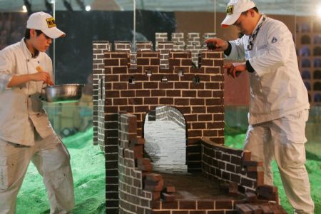 Two craftsmen are engaged in building up a 12-meter-long miniature chocolate sculpture of the Great Wall, at the World Chocolate Dream Park inside the Beijing Olympic Park, in Beijing, Jan. 14, 2010. A batch of elaborate chocolate sculptures, including the miniature replicas of Great Wall, the Terracotta Warriors, and traditional Chinese painting of Panorama Along the Upper River During the Qingming Festival in the same size to the original, are exhibited to visitors. [Xinhua]