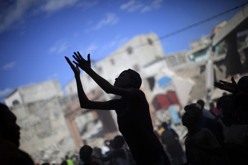A woman raises her arms for products as people loot from a destroyed shop after Tuesday&apos;s earthquake in Port-au-Prince, January 16, 2010.