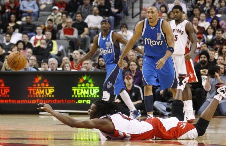 Toronto Raptors forward Chris Bosh makes a pass while falling as Dallas Mavericks' Shawn Marion (0) and Jason Terry (L) look on in front of Raptors Amir Johnson (R) during the second half of their NBA basketball game in Toronto January 17, 2010. 