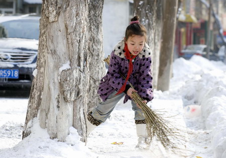 A little girl named Liu Meitong sweeps the snow in Urumqi, captical of northwest China&apos;s Xinjiang Uygur Autonomous Region, on January 19, 2010. [Xinhua]