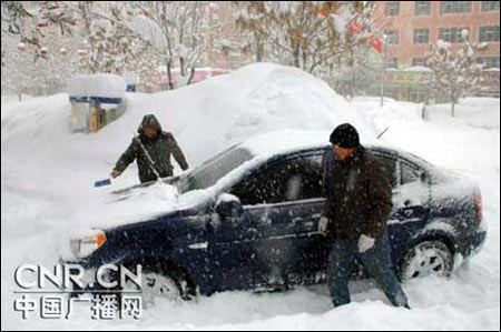 A man sweeps snow off his car in this undated photo. [cnr.cn]
