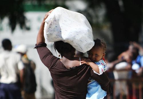 A Haitian woman carries just-received aid supplies in Port-au-Prince, Haiti, Jan. 20, 2010. (Xinhua/Xing Guangli)