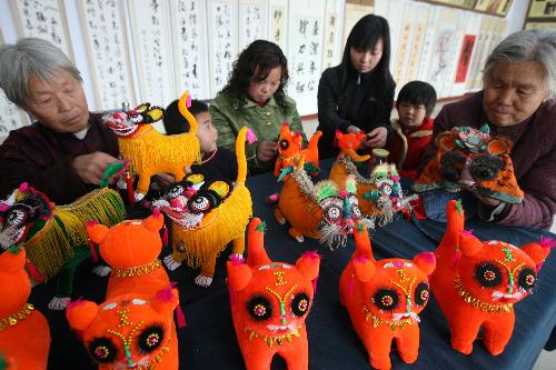 Several farmers are engrossed in elaborating tiger dolls at Guanzhuang Village, Wenxi County, north China's Shanxi Province, Jan. 19, 2010. With the approaching of the Year of Tiger according to traditional Chinese lunar calendar, local villagers start making varieties of delicate ornamental articles for the Spring Festival. [Xinhua photo]