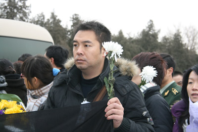 Li Xudong, one of Li Xiaoming's closest friends, holds a chrysanthemum (a traditional Chinese funeral flower) for his dead friend. [China.org.cn]