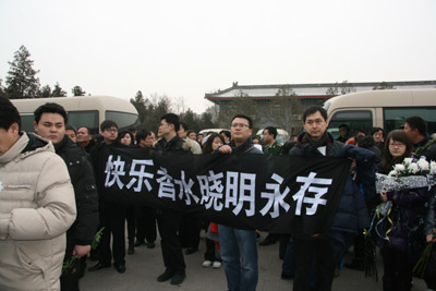 In the chilly wind, mourners hold a banner in honor of one of the peacekeepers. It reads, “Xiaoming – perfume of happiness lives forever.” [China.org.cn]