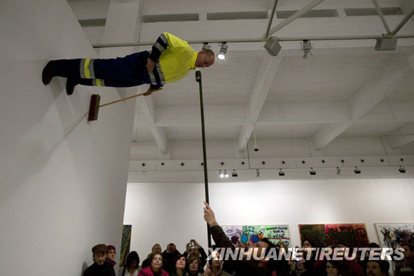 A man gives water to German artist Johan Lorbeer (top) attached to a wall during his performance &apos;Proletarisches Wandbild&apos; at the Contemporary Art Center in Malaga, southern Spain, January 20, 2010.[Xinhuanet/Reuters]