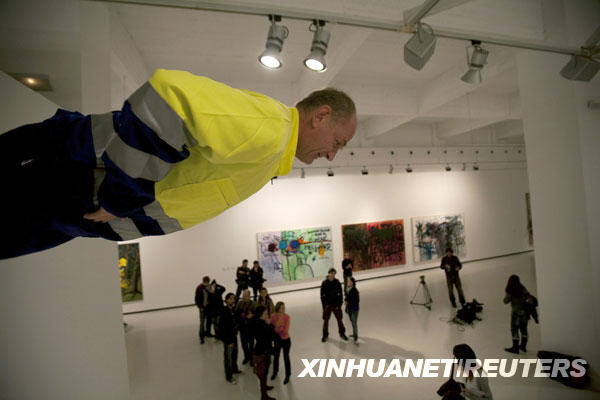 People look at German artist Johan Lorbeer attached to a wall during his performance &apos;Proletarisches Wandbild&apos; at the Contemporary Art Center in Malaga, southern Spain, January 20, 2010. [Xinhuanet/Reuters]