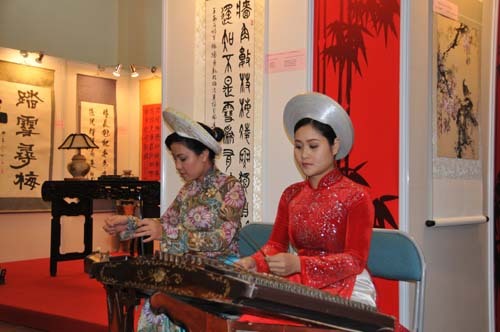 Actresses wearing traditional Vietnamese costume play the national instruments in Vietnam-China Paintings and Calligraphy Exhibition in Hanoi, capital of Vietnam, January 21, 2010. [Xinhua photo]