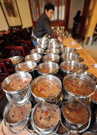 A community volunteer packs Laba porridge at Lingyin Buddhist temple in Hangzhou, capital of east China's Zhejiang province January 19, 2010, in run-up to the traditional Laba Festival that befalls on the 8th day of the 12th lunar month. The food will be handed out to locals and charity institutions for free. [Photo: Xinhua]