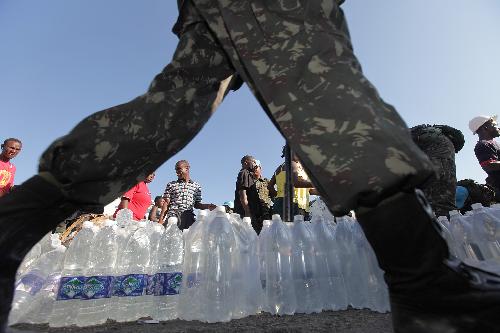 People receive water at an aid distribution site in Port-au-Prince, capital of Haiti, on Jan. 22, 2010, ten days after a catastrophic earthquake hit the nation on Jan. 12. 
