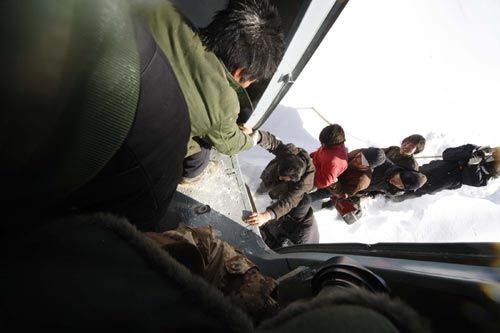 A helicopter rescues trapped people in northwest China's Xinjiang Uygur Autonomous Region, Jan. 23, 2010. Two Chinese military helicopters on Saturday delivered 10 rescuers to Altay in blizzard-hit Xinjiang to search for the missing people. The 14 people trapped in blizzard-hit areas of Xinjiang had been rescued by the military and sent to hospital for treatment.