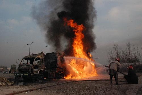 Firefighters try to extinguish a burning oil tanker truck on the outskirts of Peshawar, city of northwest Pakistan, Jan. 23, 2010. An oil tanker truck of NATO was attacked by unidentified militants on Saturday.