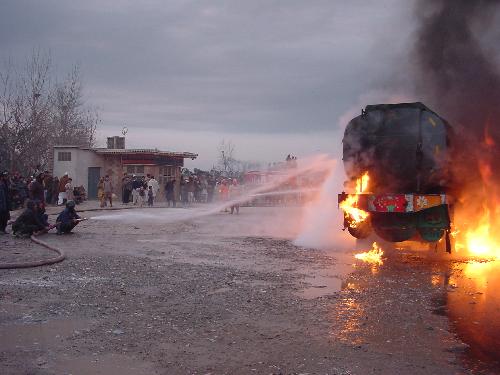 Firefighters try to extinguish a burning oil tanker truck on the outskirts of Peshawar, city of northwest Pakistan, Jan. 23, 2010. An oil tanker truck of NATO was attacked by unidentified militants on Saturday. 