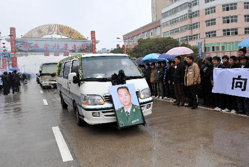 Local people hold banners to bid farewell to Zhong Jianqin, a Chinese peacekeeping police officer who were killed in the 7.3-magnitude earthquake in Haiti, as a vehicle carrying his bone ash passes by in Nanfeng county of east China's Jiangxi Province, Jan. 23, 2010. Zhong's bone ash was returned to his hometown in Nanfeng county on Saturday.