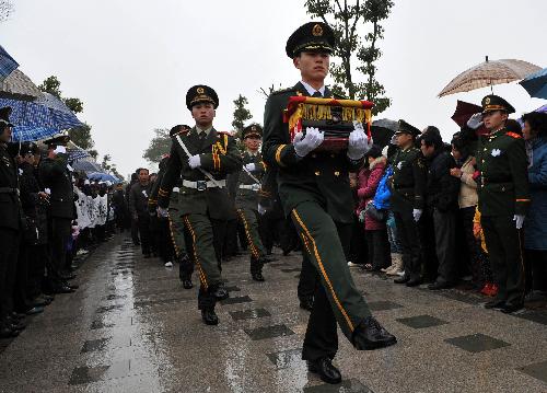 Local people gather to bid farewell to Zhong Jianqin, a Chinese peacekeeping police officer who were killed in the 7.3-magnitude earthquake in Haiti, as an armed policeman walks with his bone ash in Nanfeng county of east China's Jiangxi Province, Jan. 23, 2010. Zhong's bone ash was returned to his hometown in Nanfeng county on Saturday. 