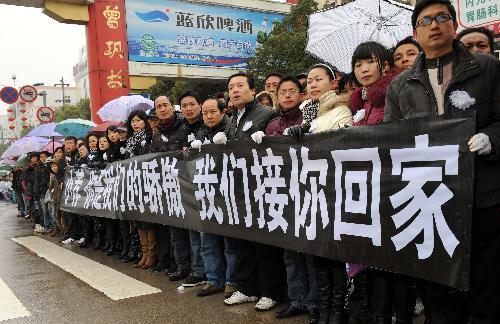 Local people hold banners to bid farewell to Zhong Jianqin, a Chinese peacekeeping police officer who were killed in the 7.3-magnitude earthquake in Haiti, in Nanfeng county of east China's Jiangxi Province, Jan. 23, 2010. Zhong's bone ash was returned to his hometown in Nanfeng county on Saturday. 