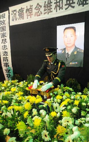 An armed policeman place the bone ash of Zhong Jianqin, a Chinese peacekeeping police officer who were killed in the 7.3-magnitude earthquake in Haiti, after it was returned to his home town in Nanfeng county of east China's Jiangxi Province, Jan. 23, 2010