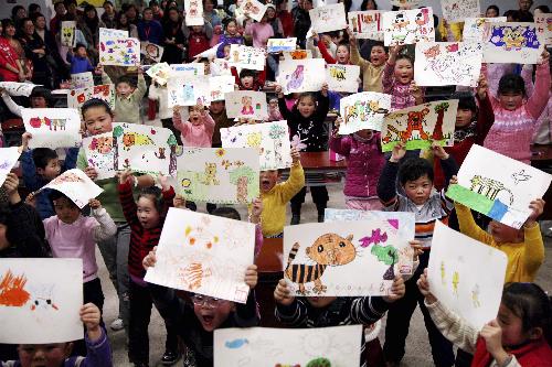 A group of children hold up their cartoon paintings of tiger in Nanjing, east China's Jiangsu Province, Jan. 23, 2010.