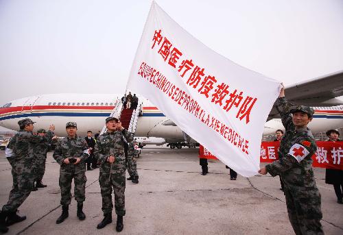Members of Chinese medical care and epidemic prevention team display their flag before they board a plane to Haiti, in Beijing, capital of China, on Jan. 24, 2010. A 40-member Chinese medical care and epidemic prevention team left here for Haiti on Sunday afternoon on a chartered flight, which also carried 20 tonnes of medical supplies. [Xinhua]