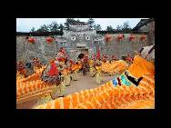 The ethnic Ke people perform folk Lion Dance in front of the tiger-shape fortress at Chebu Village of Dingnan county. (China.org.cn / CPF)