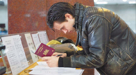 A Dutch man completes a form at the Beijing Entry-Exit Administration Bureau yesterday. [China Daily/Wang Jing]
