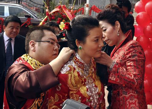 Bridegroom Li Zhaohui puts a necklace onto his bride Che Xiao, during their marriage ceremony in traditional Chinese style, in Wenxi County, Shanxi Province, Jan. 25, 2010. 