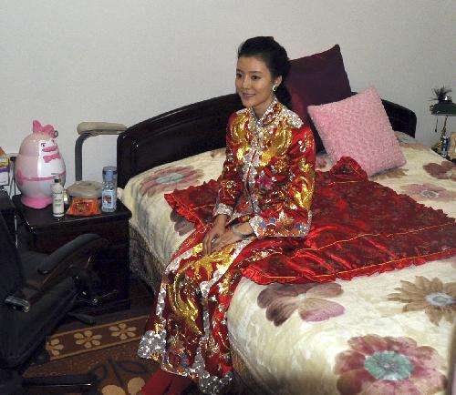 Che Xiao, bride of Li Zhaohui, sits inside the bridal chamber in traditional Chinese red wedding gown, during their marriage ceremony in traditional Chinese style, in Wenxi County, Shanxi Province, Jan. 25, 2010.