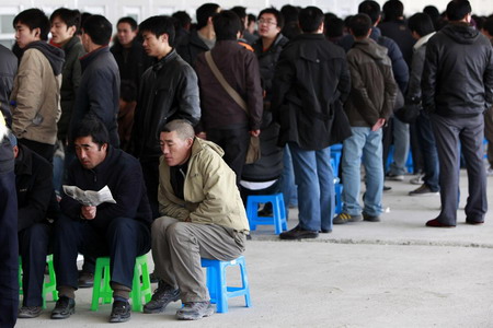 Passengers wait to buy train tickets to go home at the Shanghai Railway Station January 26, 2010. [China Daily via Agencies]