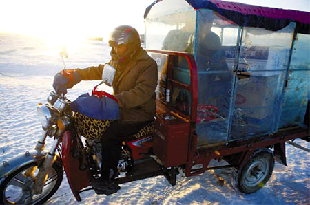 A tricycle rider ferries residents from Juhua Island across the ice to Xingcheng. [China Daily]
