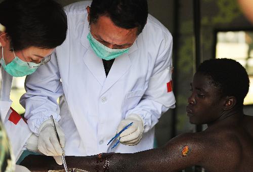 Members of a Chinese medical team work on the wound of an injured man at a makeshift hospital that the team has set up in Port-au-Prince Jan. 27, 2010. The team will stay in Haiti for weeks to provide basic medical care for survivors of the Jan. 12 earthquake. [Xinhua]