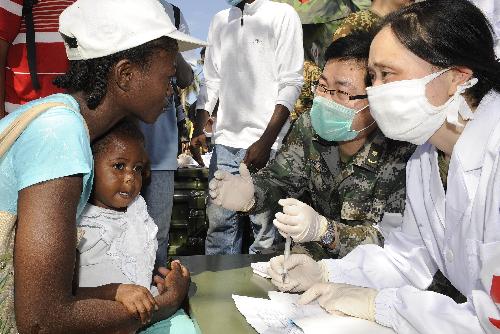 A member of a Chinese medical team asks about a child&apos;s symptoms at a makeshift hospital that the team has set up in Port-au-Prince Jan. 27, 2010. The team will stay in Haiti for weeks to provide basic medical care for survivors of the Jan. 12 earthquake. [Xinhua] 