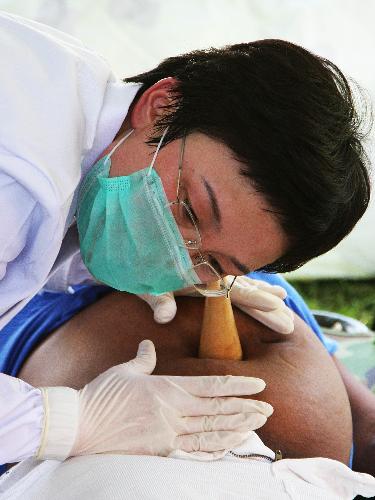 A member of a Chinese medical team performs diagnosis for a pregnant woman at a makeshift hospital that the team has set up in Port-au-Prince Jan. 27, 2010. The team will stay in Haiti for weeks to provide basic medical care for survivors of the Jan. 12 earthquake. [Xinhua] 