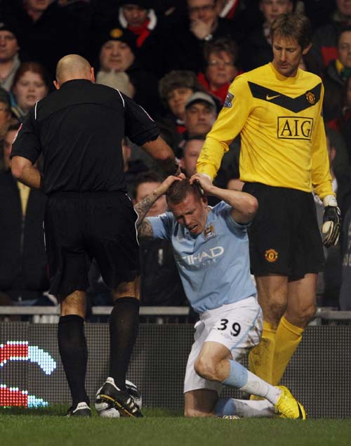 Manchester City's Craig Bellamy (C) reacts after being hit by objects from the crowd during their English League Cup soccer match against Manchester United in Manchester, northern England January 27, 2010.(Xinhua/Reuters Photo)