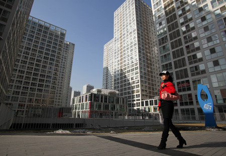 A woman passes Jian Wai Soho community. Beijing plans to collect property tax by the end of this year. [China Daily]