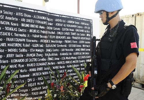 A Chinese peacekeeping policeman looks at the names of UN staff members dead in the earthquake during a memorial service in Port-au-Prince, capital of Haiti, Jan. 28, 2010. The UN confirmed on Thursday that 85 of it staff members lost their lives in the earthquake. [Xinhua]