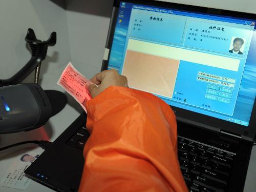 An officer verifies a passenger&apos;s real-name train ticket at the waiting area for the L7688 train going from Guangzhou to Shaoyang of central-south Hunan Province, in Guangzhou, capital of south China&apos;s Guangdong Province, Jan. 29, 2010.