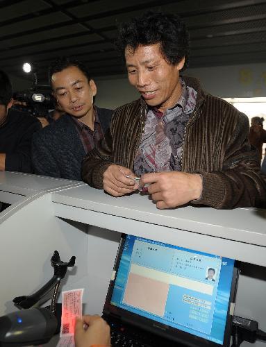 A passenger (R) waits for his real-name train ticket to be verified at the waiting area for the L7688 train going from Guangzhou to Shaoyang of central-south Hunan Province, in Guangzhou, capital of south China&apos;s Guangdong Province, Jan. 29, 2010. 