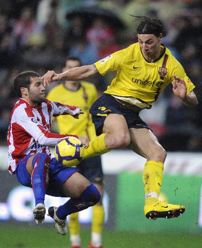 Barcelona's Zlatan Ibrahimovic (R) and Sporting Gijon's Alberto Lora jump for the ball during their Spanish First Division soccer match at El Molinon stadium in Gijon January 30, 2010.(Xinhua/Reuters Photo)