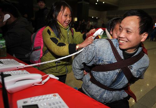 Lu Laofa (R), a 40-year-old migrant worker from southwest China's Guizhou Province, and his children make a free phone call with their relatives at the railway station of Hangzhou, capital of east China's Zhejiang Province, Jan. 31, 2010. The railway station provides free phone call service for migrant workers during the Spring Festival travel peak. Some 20 million migrant workers in Zhejiang Province began to return home for Spring Festival which falls on Feb. 14 this year. 