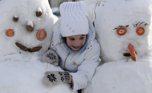 A girl plays with snowmen built as part of a display on a street in Moscow January 31, 2010.[Xinhua/Reuters]