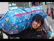 A migrant worker waits to board a train with his big luggage at railway station of Yantai, north China's Shandong Province on January 29, 2010.